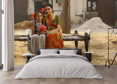 woman sitting with her daughter in Rural Environment wearing a saree which is traditional Dress for women in North India in day time holding a laptop Wall mural