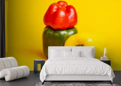 Couple of yellow, red and green colorful peppers stacked on top of each other. Studio food still life contrasted against a seamless dark yellow background. Wall mural