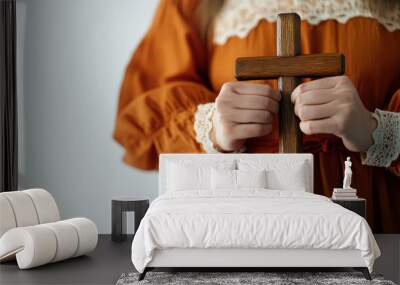 Woman holding wooden cross in prayerful hands with soft focus background Wall mural