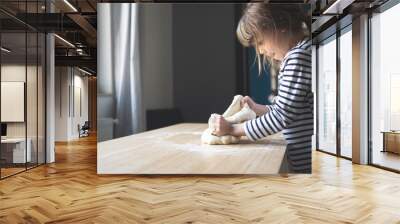 little Caucasian girl working the dough on a wood cutting board Wall mural