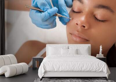 Cropped close up of a beautiful African woman getting facial skincare treatment at beauty salon Wall mural