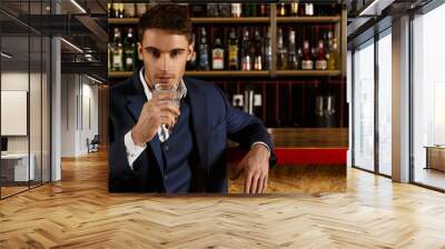 His look leaves you motionless. Handsome young man having a drink at the bar looking at the camera confidently copyspace on the side Wall mural