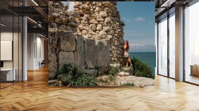 A girl in a dress goes to the ancient ruins of the fortress. Tourism in Crimea. Travel around Europe. Wall mural