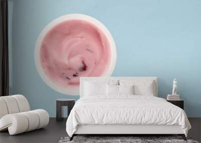 Yogurt in plastic cup close up - top view photo of strawberry yoghurt on pale blue background Wall mural