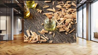 A bottle of cedar essential oil with pieces of cedar wood Wall mural