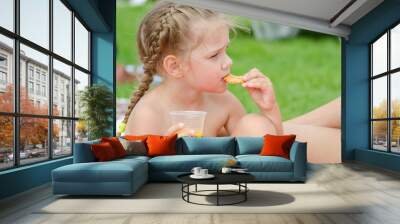 Girl eating cookies and drinking juice from a plastic disposable cup Wall mural