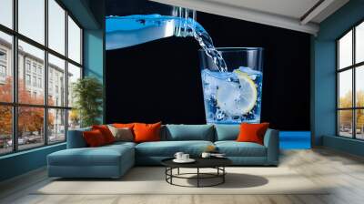 Pouring water into a glass on a white background with copy space Wall mural