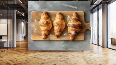 Freshly baked croissants on wooden cutting board over grey background, top view Wall mural