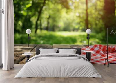 Wooden table with red checkered tablecloth on nature background Wall mural