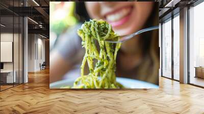 Detailed close-up of a woman relishing a forkful of aromatic basil pesto pasta Wall mural