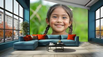 Indigenous child girl with tan skin and braided hair, smiling on a green background 2 Wall mural