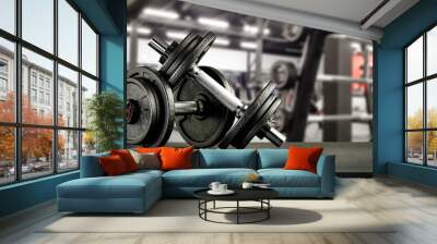 Black desk of free space for your decoration and blurred gym interior.Metal dumbbells and fit life  Wall mural