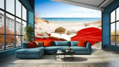 Red towel on beach and book with summer hat.  Wall mural