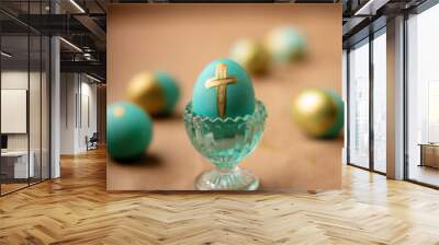 Teal Easter egg with gold cross isolated on a blurred background Wall mural