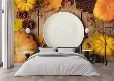 Autumn background with plate, fall leaves and pumpkin over wooden table. View from above Wall mural