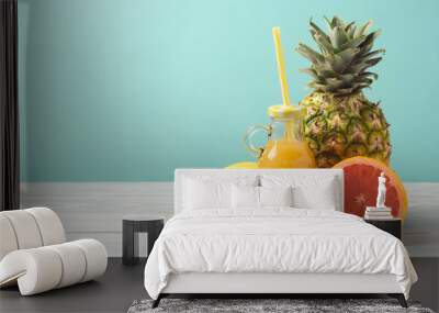 Pineapple, juice and grapefruit on wooden table over mint background. Summer detox diet concept Wall mural