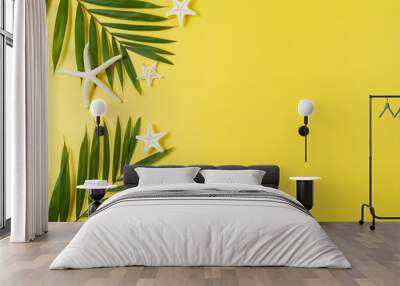 Tropical summer vacation concept with palm tree leaves and starfish on yellow background. Top view from above Wall mural