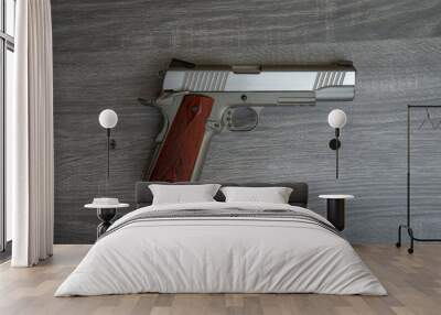 Stainless hand gun with brown hand grip is on the wooden floor Wall mural