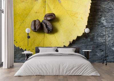 Coffee beans on a fallen yellow leaf in autumn. Wall mural