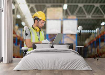 A male manager is checking inventory inside a warehouse. Wall mural