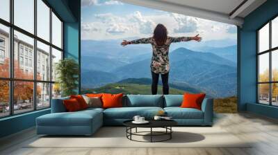 Girl traveling in mountains alone, standing with hands up achieving the top, welcomes a sun. Walking outdoors, woman hiker on mountain top. Wanderlust theme. Carpathian mountains, Hoverla, Ukraine. Wall mural