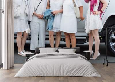 People dressed in white posing next to limousine. Body parts, white party Wall mural