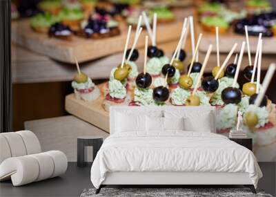 Wooden tray of appetizers on pallet coffee table at banquet with jamon, butter cream and olives. Selective focus. Wall mural