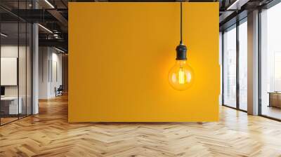 A single hanging light bulb displayed against a yellow background, symbolizing creativity or the concept of a bright idea. Wall mural