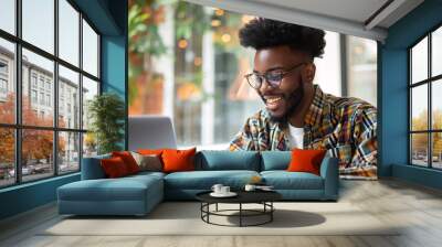 Young Smiling Man Typing on Laptop: A young man smiling while typing on a laptop Wall mural