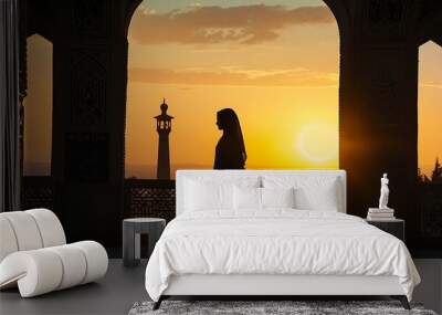 Silhouette of muslim woman praying at sunset in the mosque. Wall mural