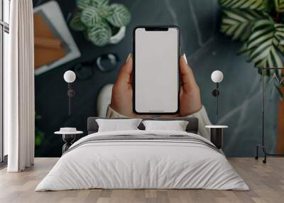 Top view of female hands holding smartphone with blank screen on white wooden table background Wall mural