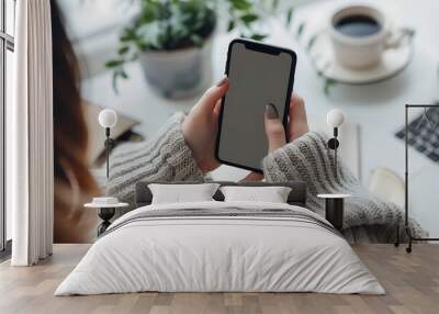 Top view of female hands holding smartphone with blank screen on white wooden table background Wall mural