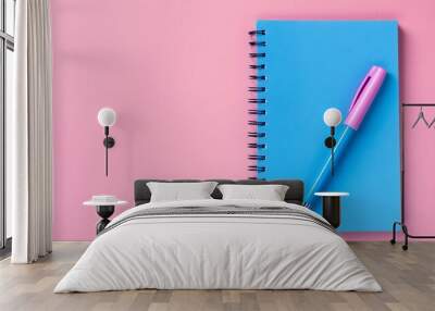 Blue notebook and pen on pink background Wall mural