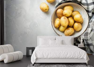 Bowl with fresh ripe potatoes and knife on light background Wall mural