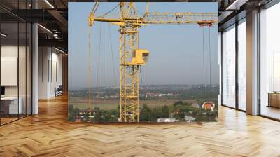 Old construction crane on the background of green nature and blue sky Wall mural