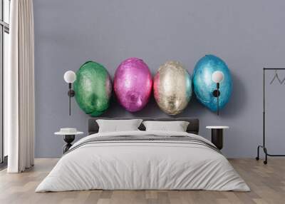 chocolate candies in foil in the form of Easter eggs on a gray background Wall mural