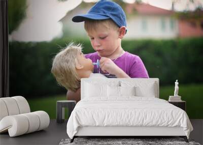 little boy playing with a doll in nature Wall mural