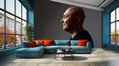 Portrait of a bald cheerful man in profile on a black background Wall mural