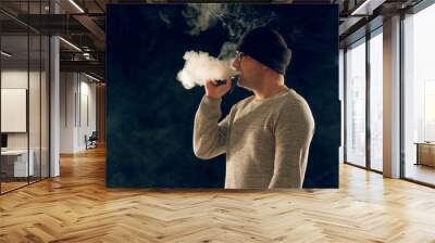 smoking man in e-cigarette smoke on black background Wall mural