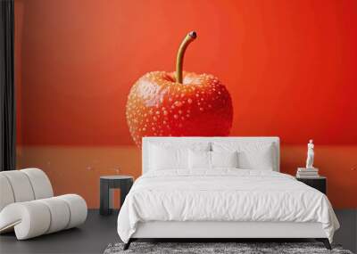 A close-up of a shiny red apple on a vibrant orange background, symbolizing freshness and health, perfect for food-related marketing or wellness themes. Wall mural