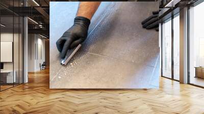 close up of professional cleaner cleaning grout with a brush blade and foamy soap on a gray tiled bathroom floor Wall mural