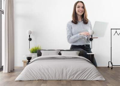 A girl in a good mood is sitting on a table and typing on a computer on a white background Wall mural