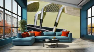 A picturesque snapshot featuring a set of golf clubs thoughtfully organised within a sleek bag. Against the backdrop of the emerald fairway. Wall mural