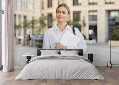 A pretty young woman with white hair dressed in a white shirt and black jeans carries a laptop with her Wall mural