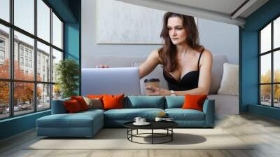 Young woman working at home on laptop and drinking coffee Wall mural