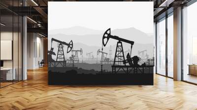 Oil pumps at large oilfield over mountain range.  Wall mural