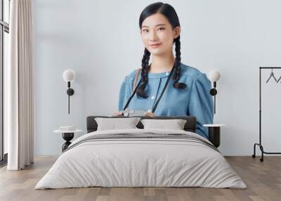 A happy and smiling young woman using a digital camera isolated on a white background. Wall mural