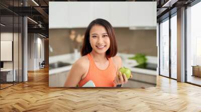 Asian woman holding apple and scale in the kitchen Wall mural