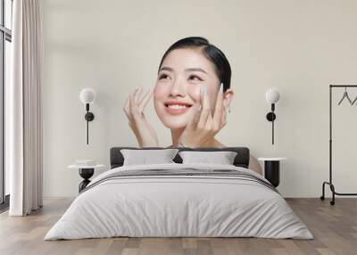 Beautiful young woman with clean fresh skin touching her face Wall mural