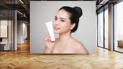 Beauty concept. Asian pretty woman with perfect skin holding cosmetic bottle Wall mural